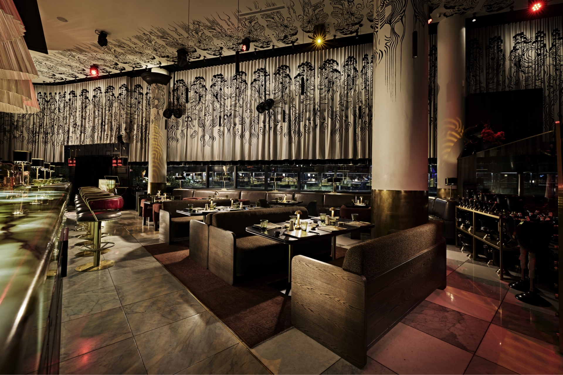 An elegant upscale event venue in Sandton with modern booth seating, a marble bar, and a stylish interior featuring artistic ceiling and curtain patterns.