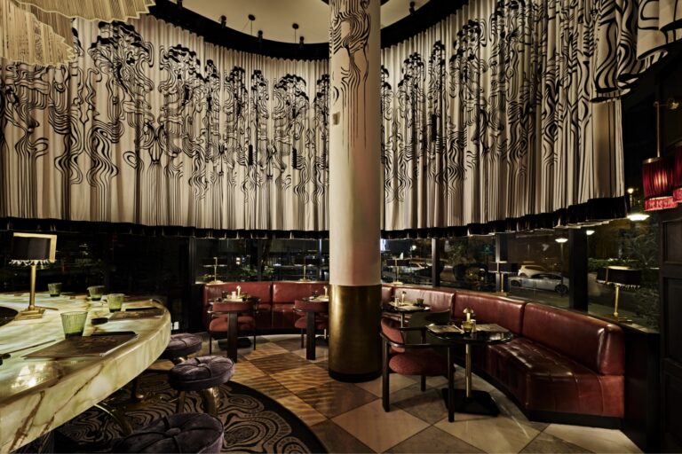 An elegant upscale event venue in Sandton with modern booth seating, a marble bar, and a stylish interior featuring artistic ceiling and curtain patterns.